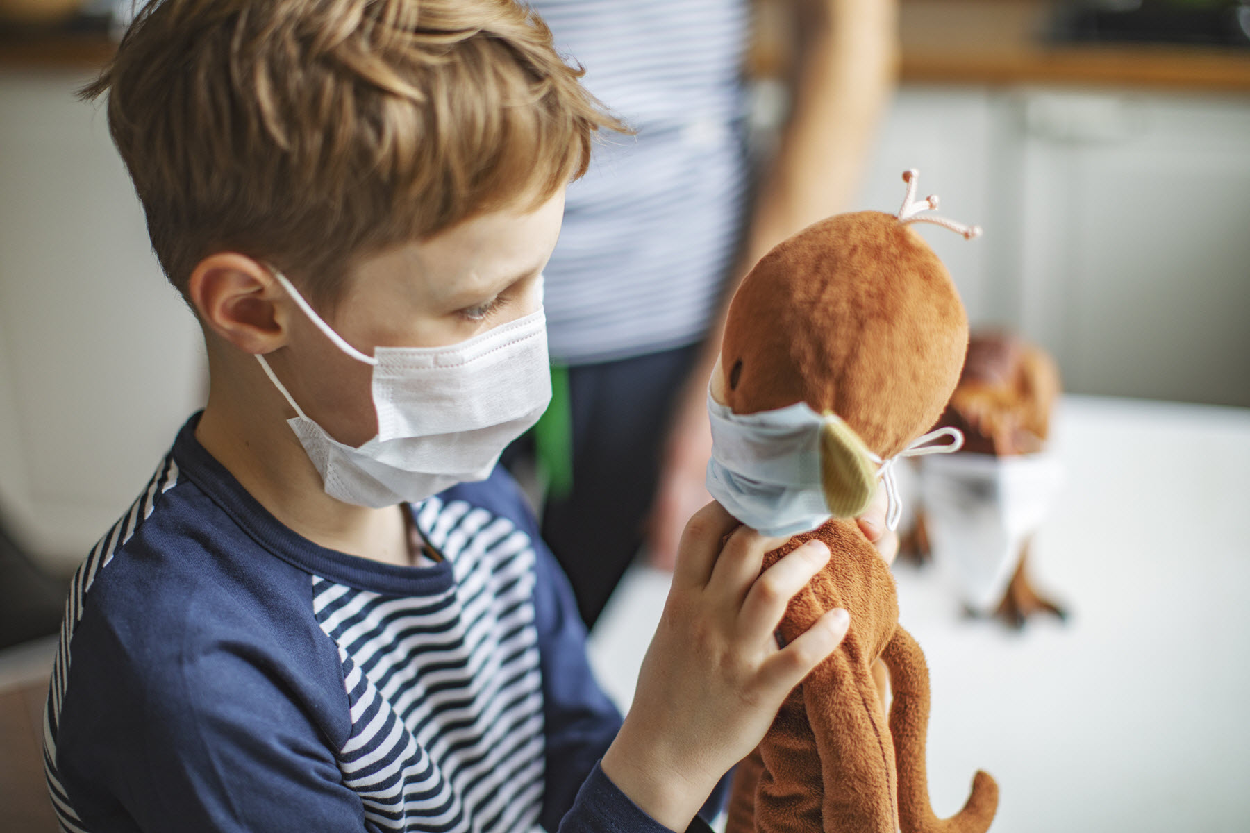 child in face mask with teddy bear